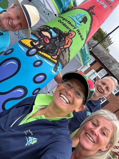 4 people stood around a painted kayak smiling