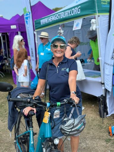 Lady smiling with her bike wearing Hengistbury Head outdoors merchandise